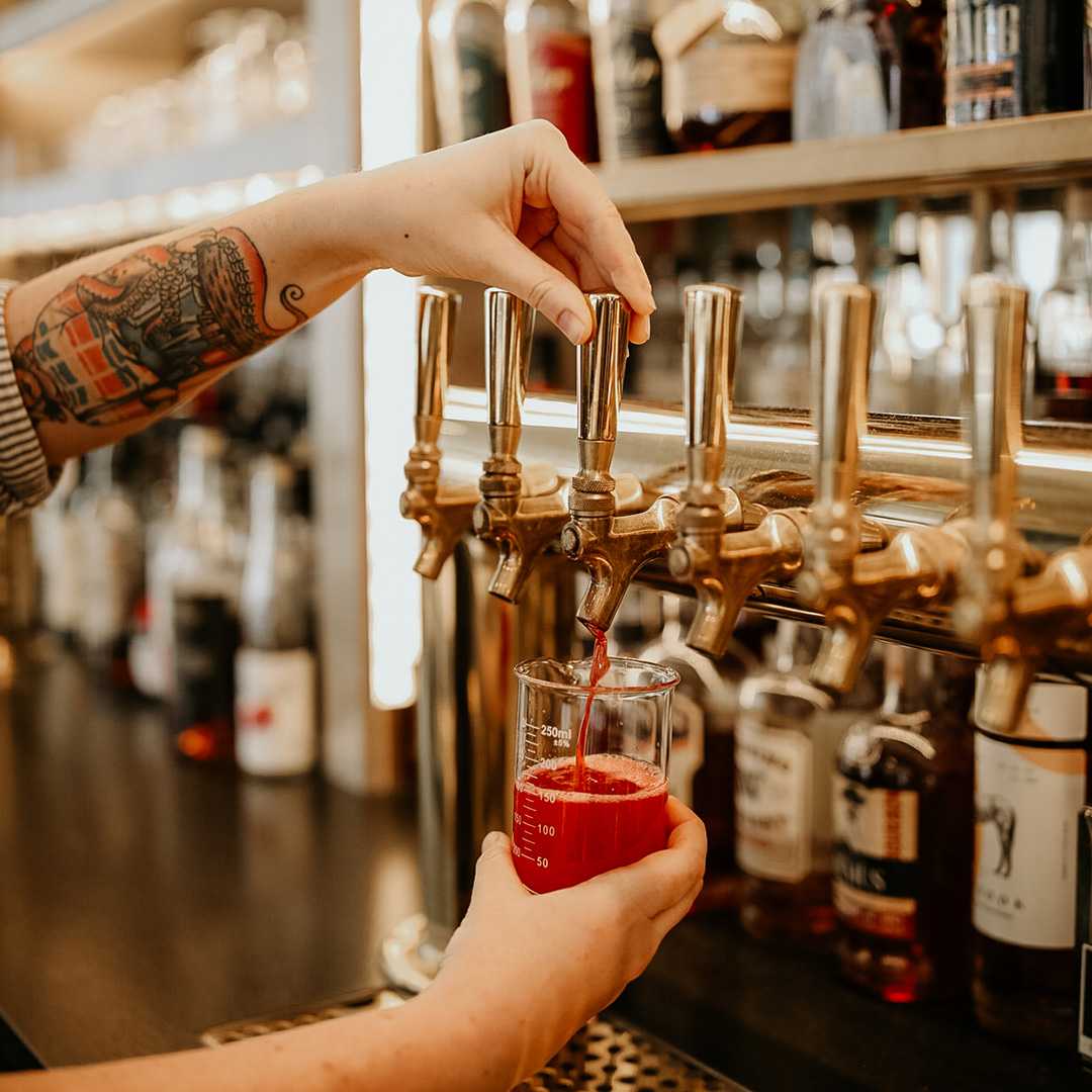 A photo of a bartender pouring a bright pink mixed cocktail into a beaker glass. Photo is from our chattanooga photography marketing package.